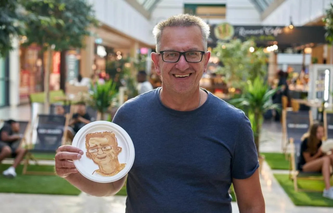 Lächelnder Gast in einer Shopping-Mall hält sein Pancake Portrait in der Hand