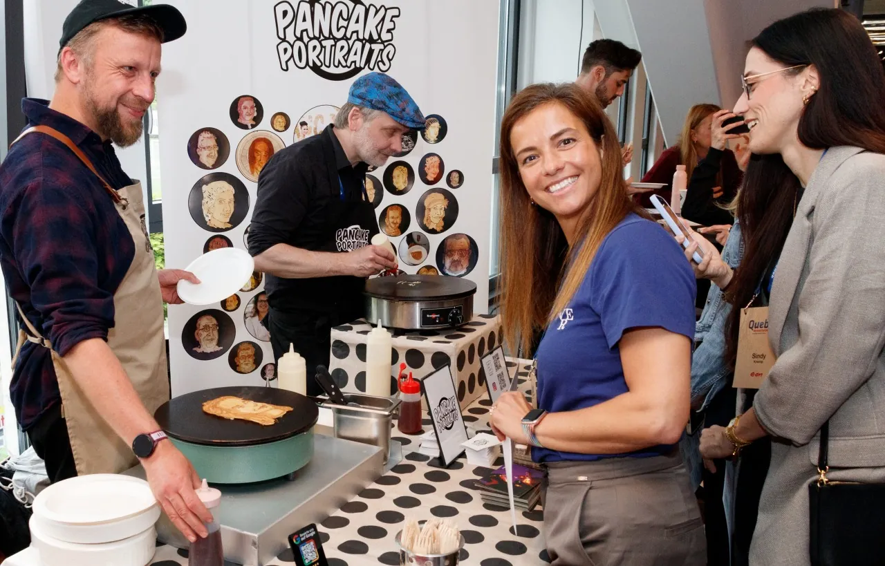 Pancake-Portraits-Messestand mit zwei Künstlern, einer Wand voller Porträts und Gästen